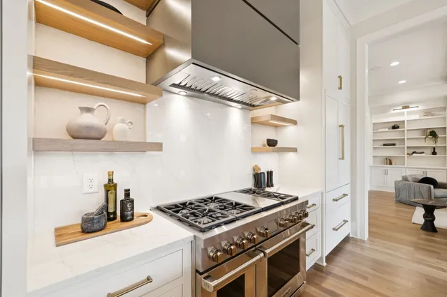 a room with kitchen island stainless steel appliances cabinets and wooden floor