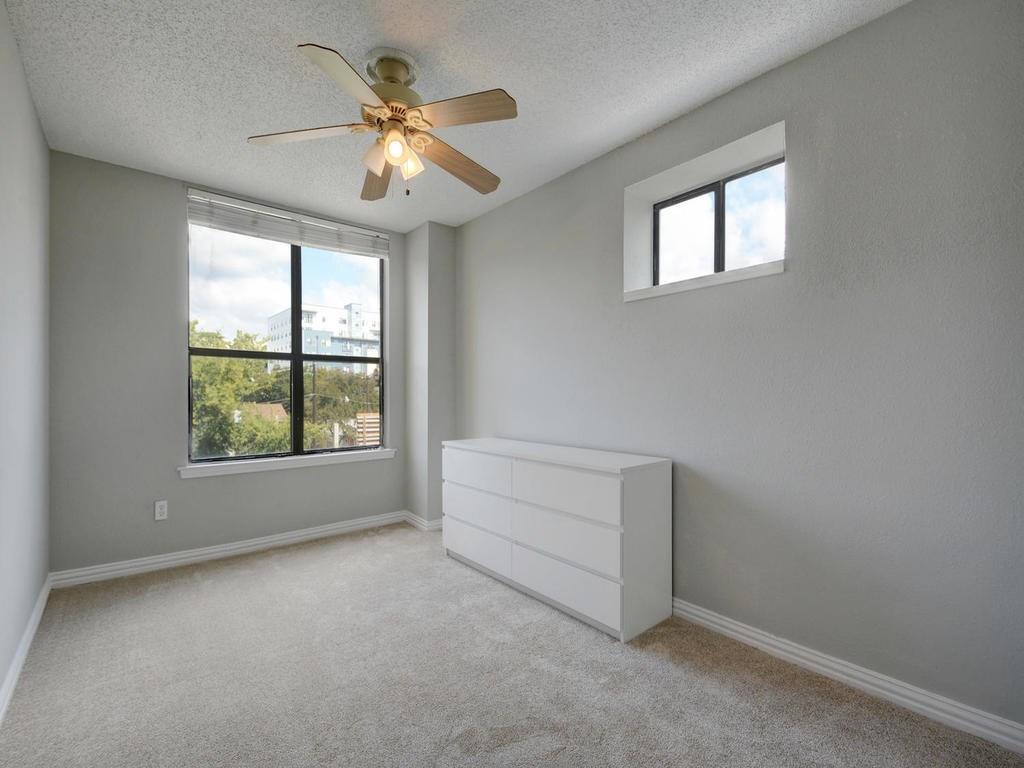 2409 Leon Street, Unit 207 Austin, TX 78705 - Photo 13 of 18 an empty room with windows and chandelier fan
