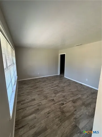 an empty room with wooden floor and entrance