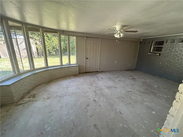 an empty room with chandelier fan and windows