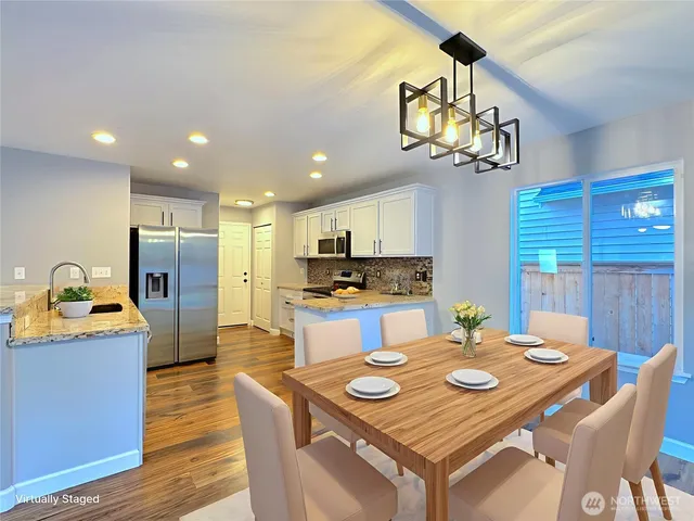 a kitchen with stainless steel appliances kitchen island granite countertop a kitchen island a stove a table and chairs