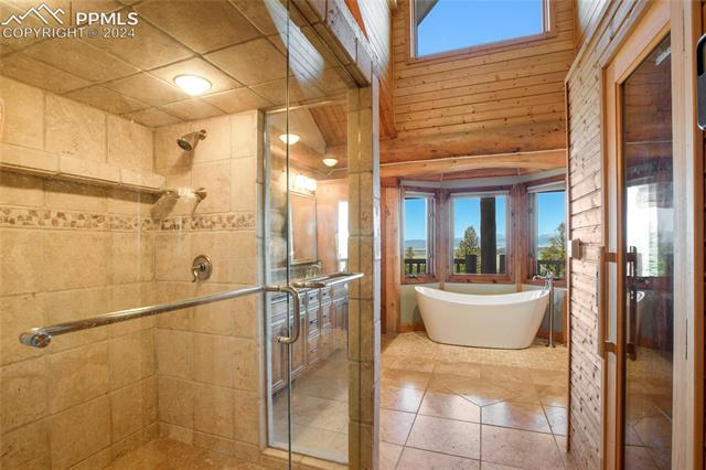616 Summit Road Hartsel, CO 80449 - Photo 29 of 50 Bathroom with independent shower and bath, tile patterned floors, and wooden walls
