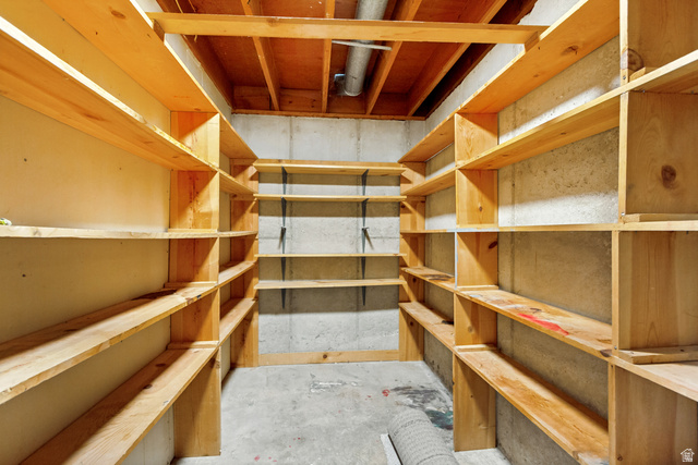 62 South Clark Lane Elk Ridge, UT 84651 - Photo 27 of 30 Utility space featuring extensive wood shelving, concrete walls, concrete flooring, and exposed ceiling joists