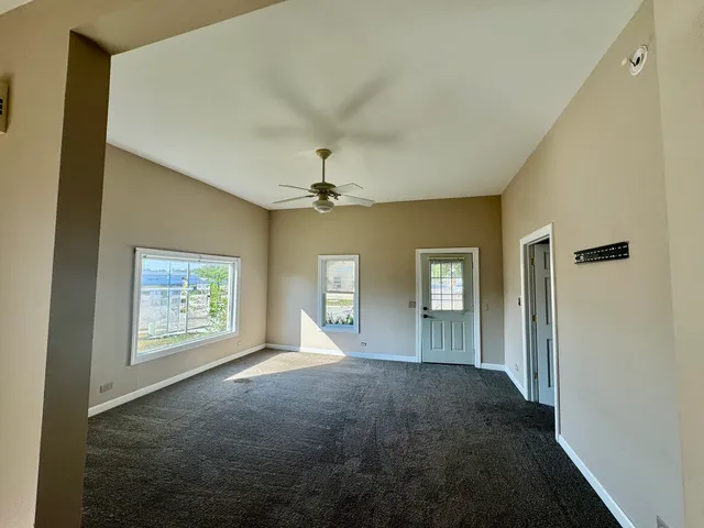 a view of empty room with windows and ceiling fan