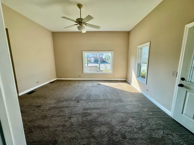 an empty room with windows and fan