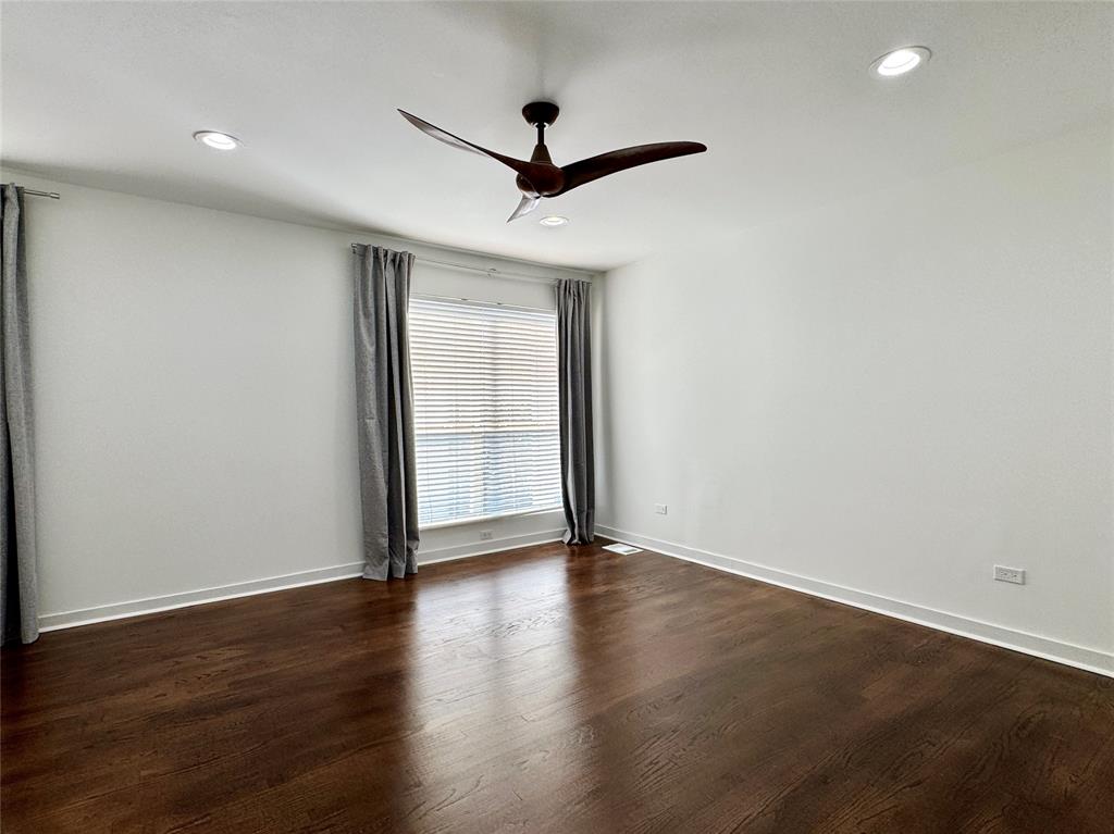 4134 Travis Street, Unit 2 Dallas, TX 75204 - Photo 9 of 28 a view of an empty room with wooden floor and a ceiling fan