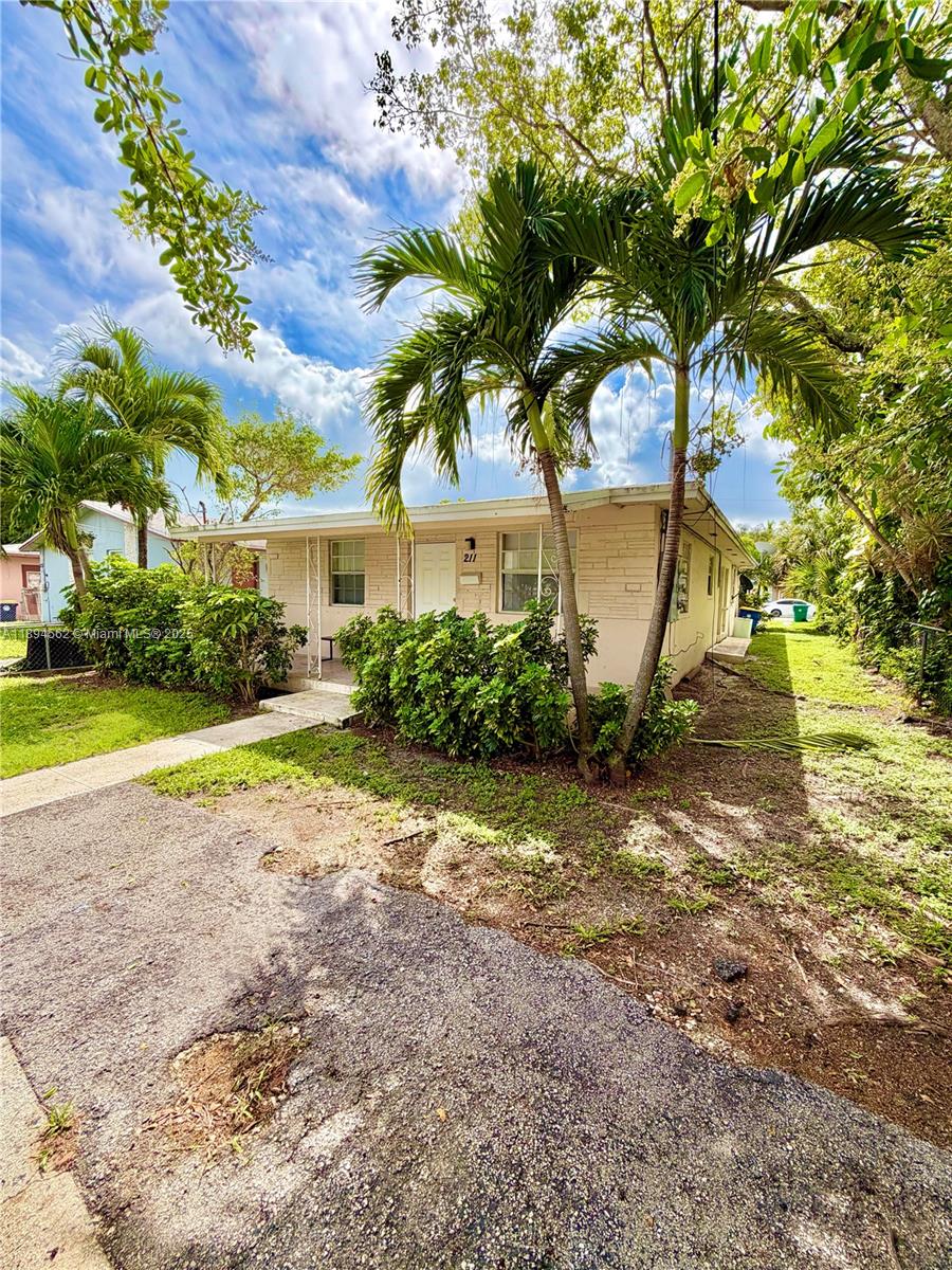 211 Stirling Road, Unit 1 Dania Beach, FL 33004 - Photo 1 of 21 a view of a house with a big yard and large trees