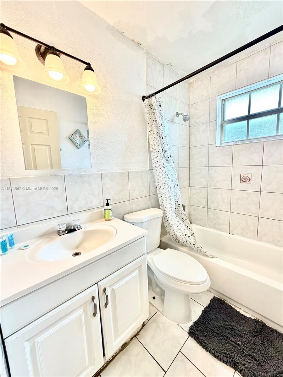 211 Stirling Road, Unit 1 Dania Beach, FL 33004 - Photo 13 of 21 a bathroom with a sink a toilet a mirror a vanity and bathtub
