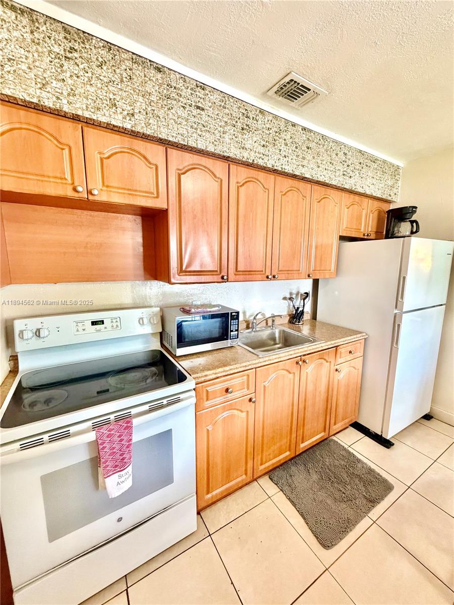 211 Stirling Road, Unit 1 Dania Beach, FL 33004 - Photo 6 of 21 a kitchen with a stove a sink and a refrigerator