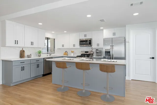 a kitchen with kitchen island granite countertop a sink a counter top space and stainless steel appliances