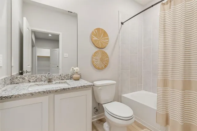 a bathroom with a granite countertop toilet sink vanity and mirror