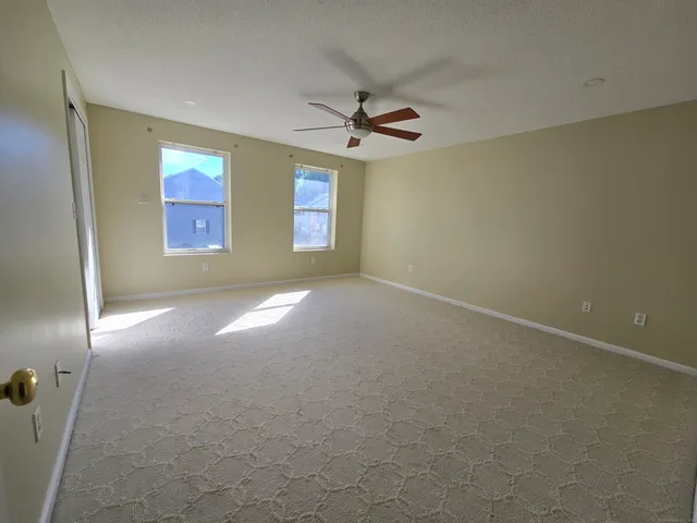 an empty room with windows and fan