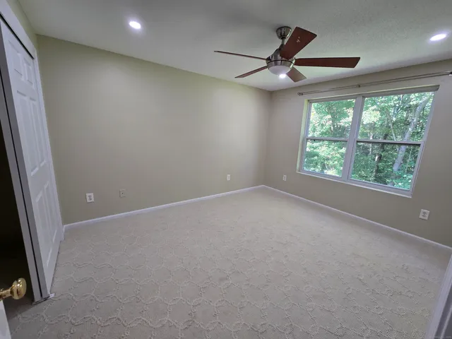 an empty room with a ceiling fan and window