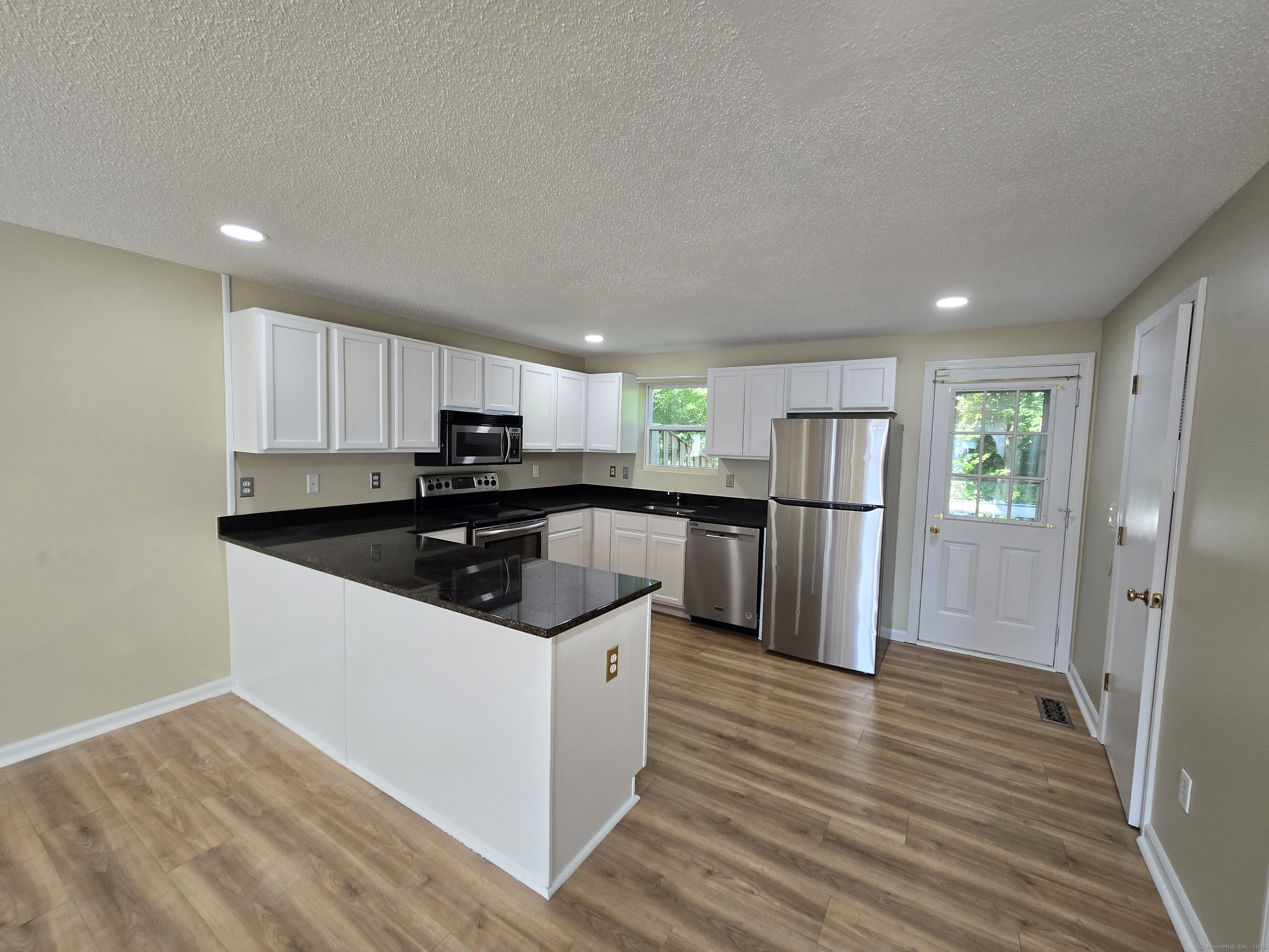 5 Periwinkle Lane, Unit 5 Glastonbury, CT 06033 - Photo 8 of 23 a kitchen with stainless steel appliances granite countertop a refrigerator a sink dishwasher a stove and white countertops with wooden floor