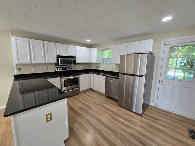 a kitchen with a refrigerator a stove top oven and white cabinets