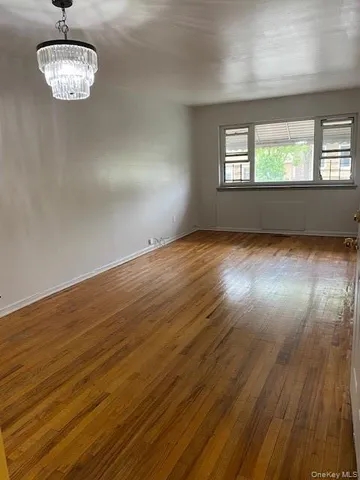 a view of empty room with wooden floor and window