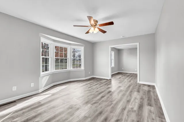 a view of empty room with wooden floor and fan
