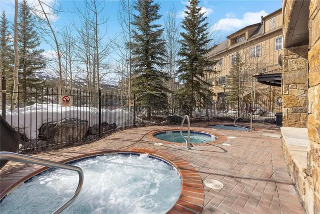 a backyard of apartments with large trees and wooden fence