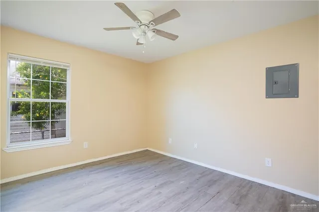 a view of an empty room with a window and wooden floor