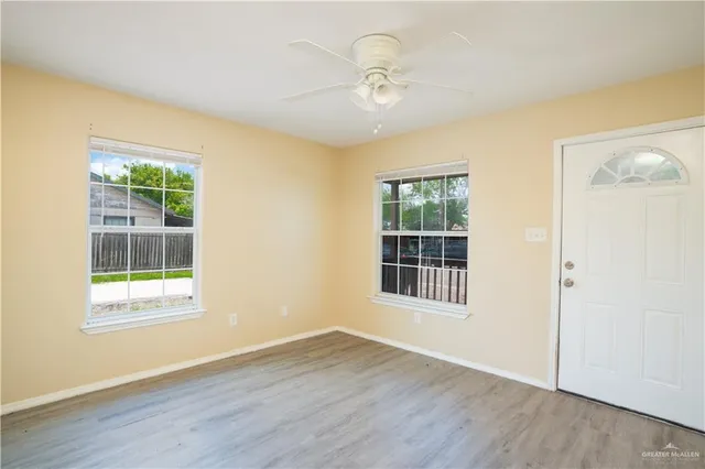a view of an empty room with wooden floor and a window