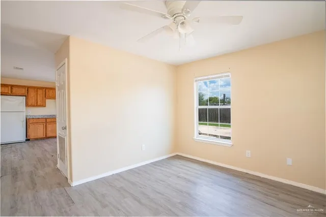 a view of an empty room with a window and wooden floor