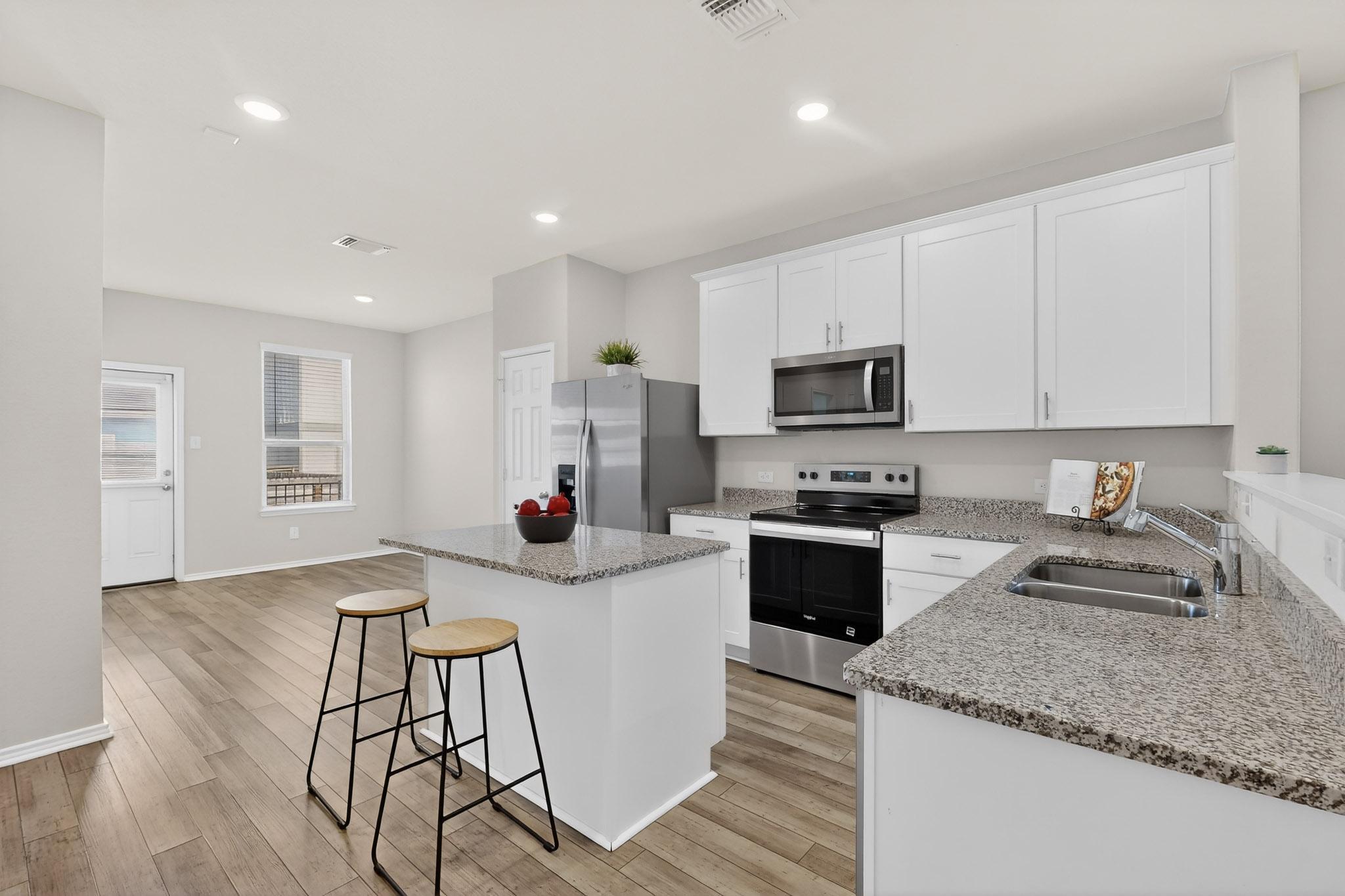 429 Stone Water Lane Jarrell, TX 76537 - Photo 10 of 37 a kitchen with stainless steel appliances granite countertop a stove top oven a sink a refrigerator and white cabinets with wooden floor