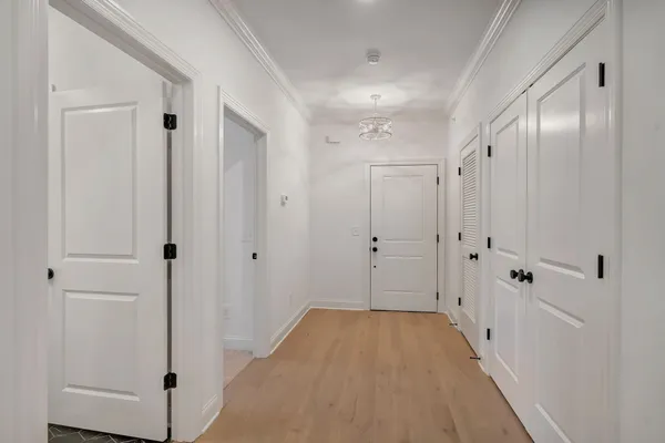 a kitchen that has a sink a microwave oven a stove and white cabinets with wooden floor