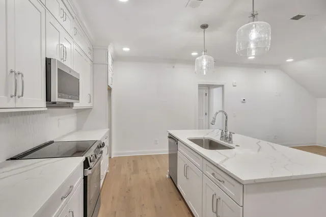 a large kitchen with kitchen island a stove a sink a center island and wooden floor