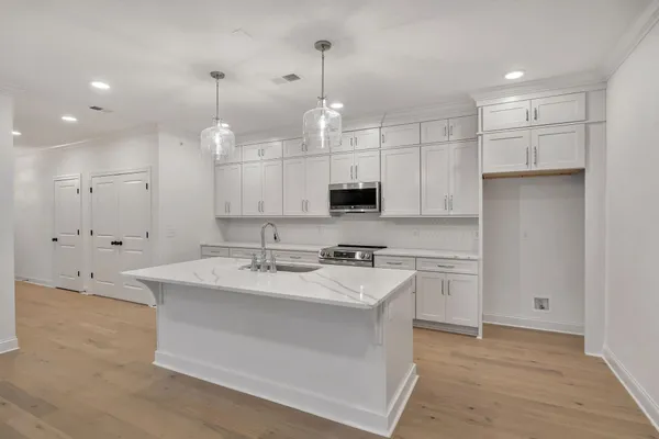 a view of a kitchen island a sink wooden floor and a large window