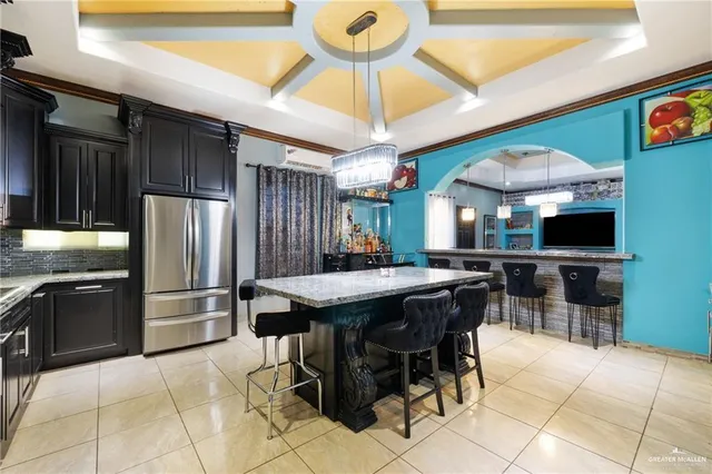 a kitchen with stainless steel appliances kitchen island granite countertop a table chairs and a refrigerator