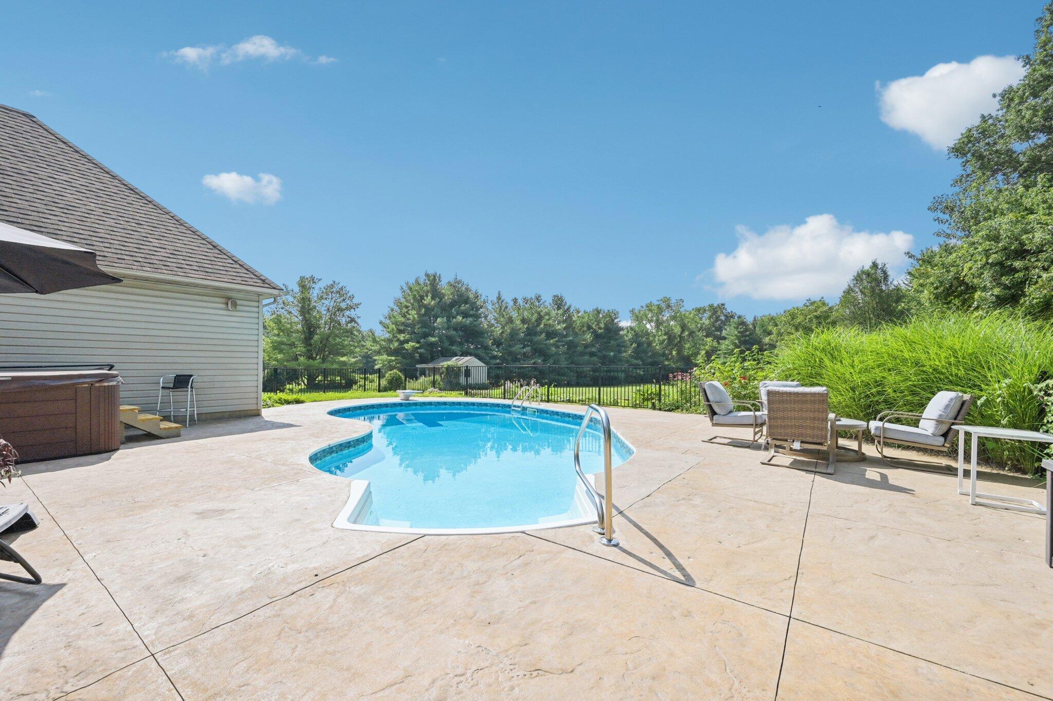 7700 Plumb Road Galena, OH 43021 - Photo 12 of 94 Beautiful in-ground pool surrounded by a stamped concrete patio, lush landscaping, and ample space for poolside seating and entertaining.