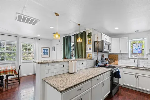 a kitchen with a sink stove and wooden floor