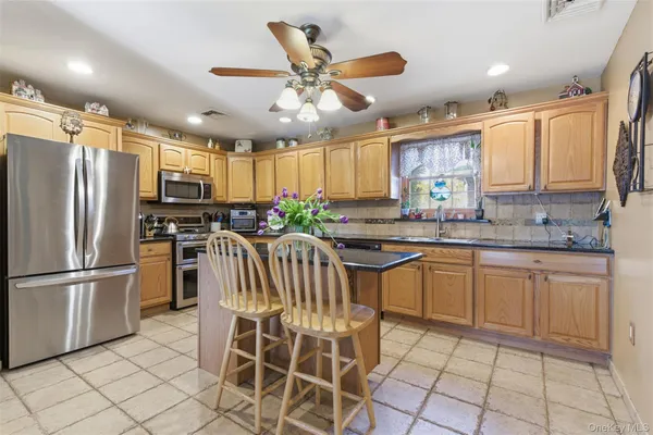 a kitchen with granite countertop stainless steel appliances a sink a counter top space cabinets and a window