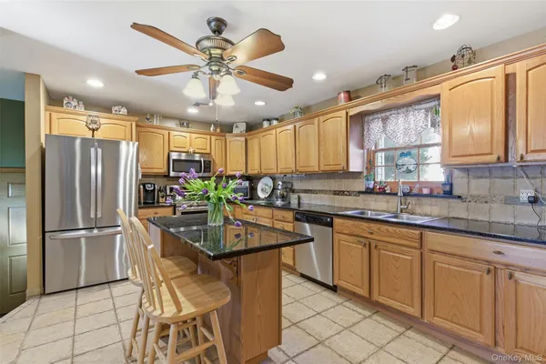 a kitchen with stainless steel appliances granite countertop a sink a stove a refrigerator cabinets and dining table