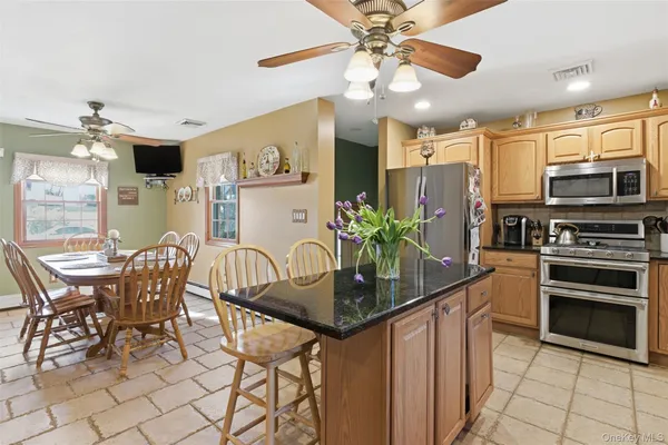 a kitchen with stainless steel appliances kitchen island granite countertop a table chairs and a refrigerator