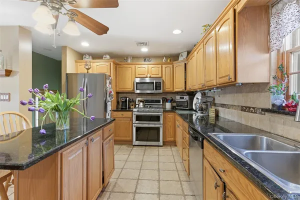 a kitchen with stainless steel appliances granite countertop a sink counter space cabinets and a large window