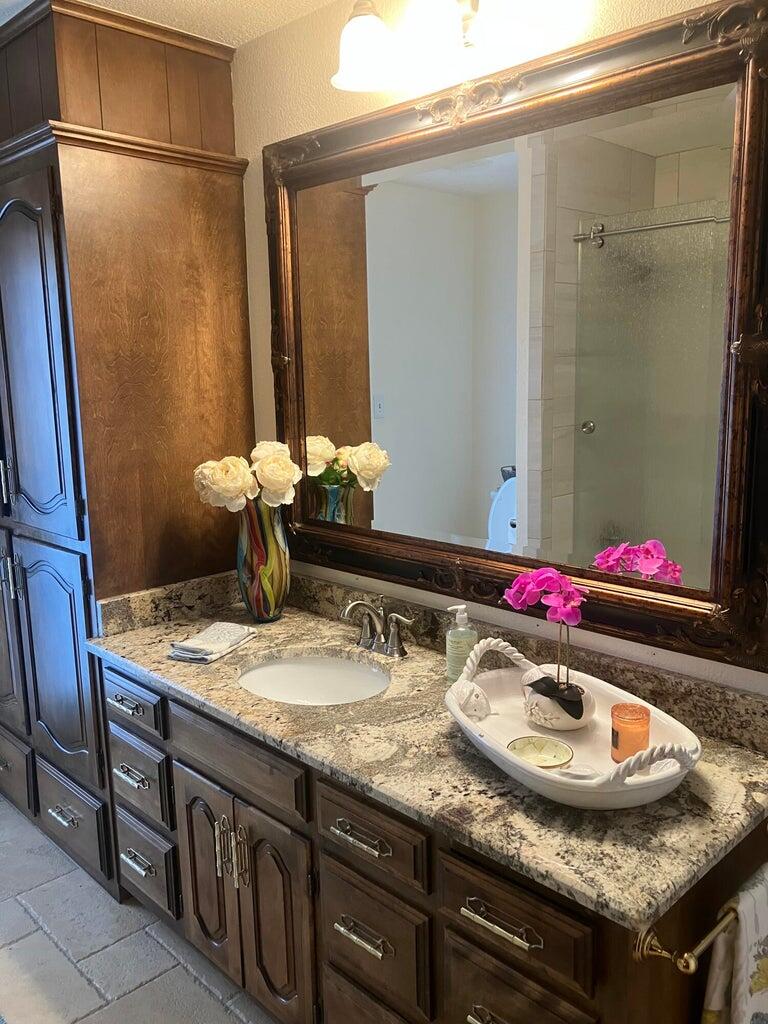 7303 Olton Road Plainview, TX 79072 - Photo 27 of 56 a bathroom with a granite countertop sink a mirror and shower