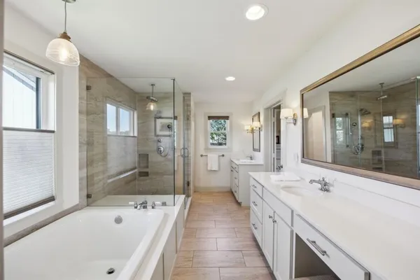 a large spacious bathroom with a tub sink shower and mirror