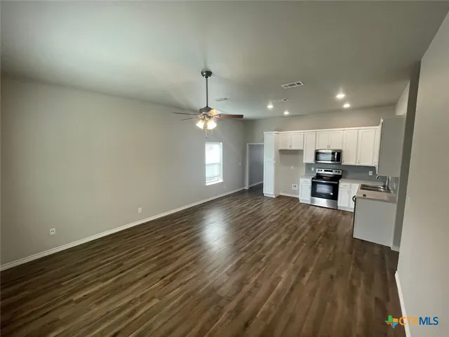 a view of kitchen and empty room with wooden floor