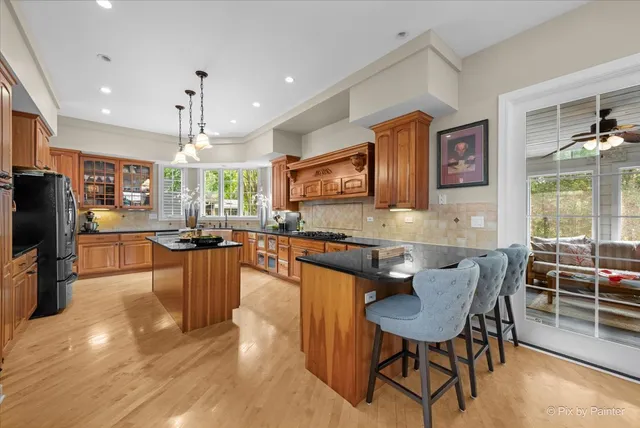 a dining hall with stainless steel appliances granite countertop a stove a sink a dining table and chairs with wooden floor