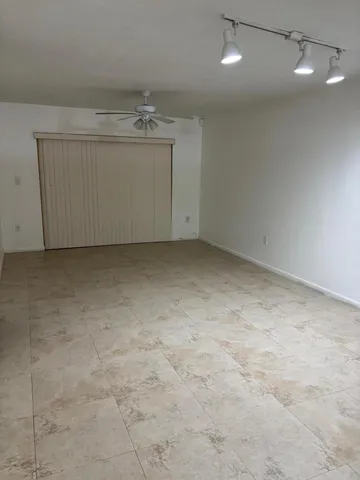 an empty room with a chandelier fan and windows