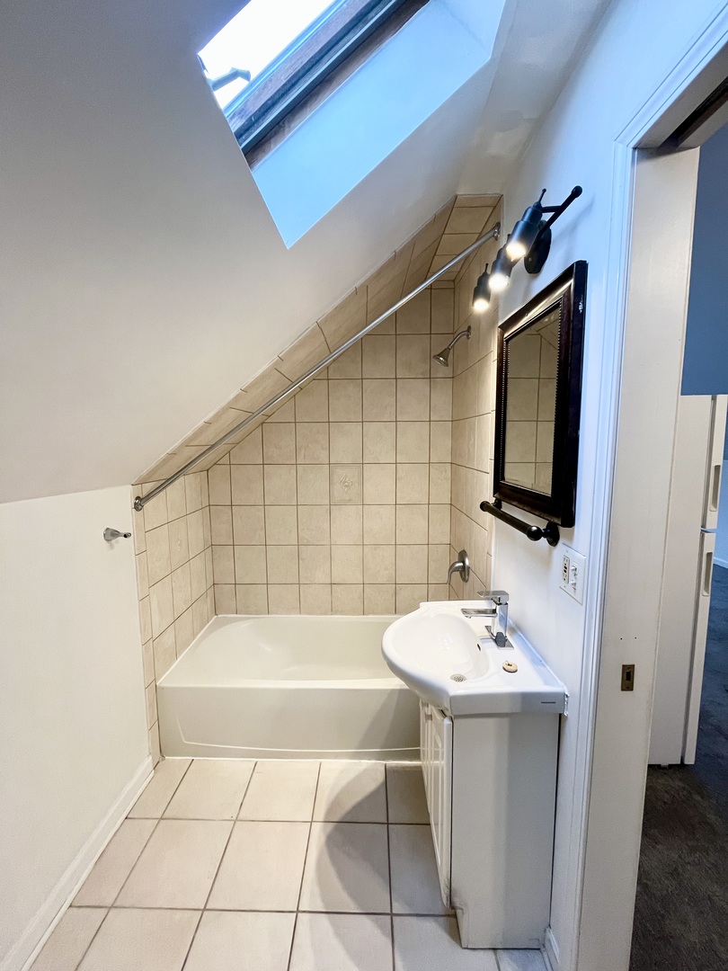 3227 South Carpenter Street, Unit 4F Chicago, IL 60608 - Photo 8 of 12 a bathroom with a sink a mirror and a bathtub