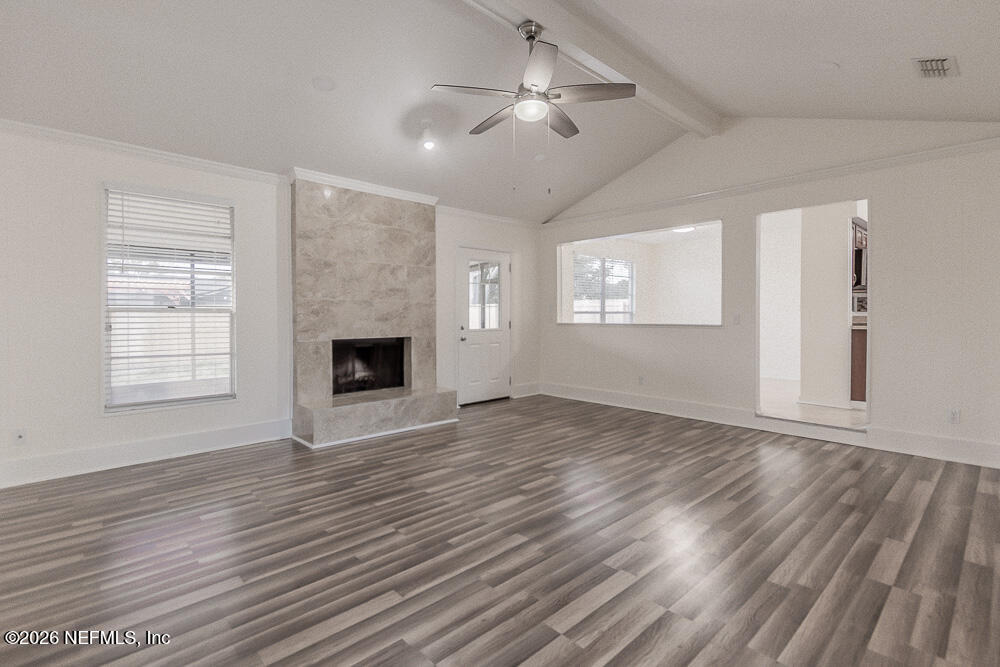 8209 Worm Wood Road Jacksonville, FL 32210 - Photo 15 of 44 an empty room with wooden floor chandelier fan and windows