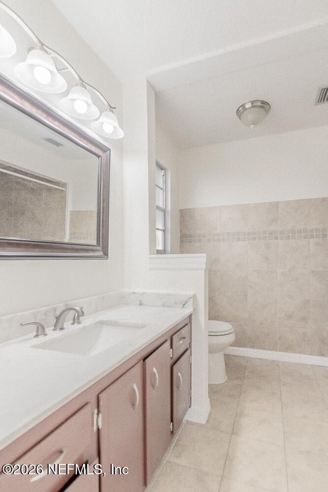 8209 Worm Wood Road Jacksonville, FL 32210 - Photo 5 of 44 a bathroom with a granite countertop toilet sink and mirror