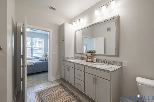 a en suite bathroom with a granite countertop sink a toilet and a mirror