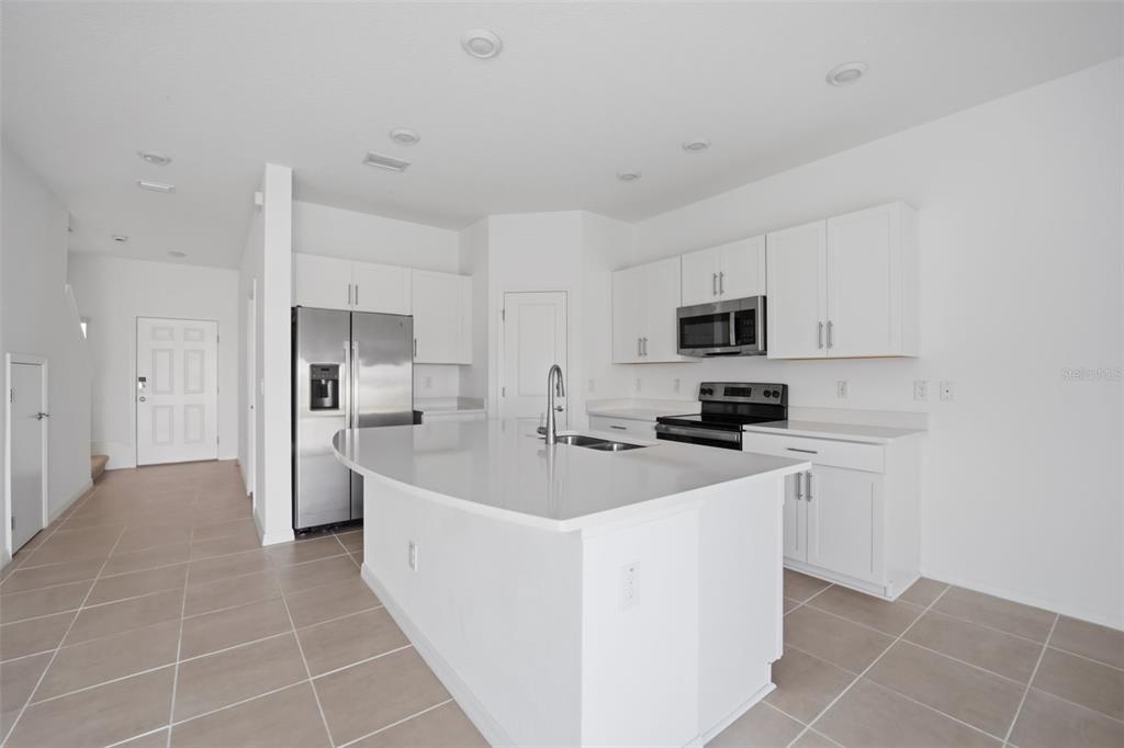 2407 Paravane Way Wesley Chapel, FL 33543 - Photo 4 of 32 a large white kitchen with stainless steel appliances a sink a stove a microwave and cabinets