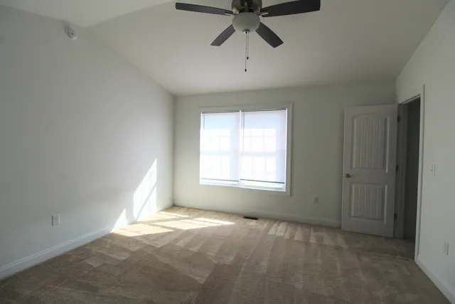 an empty room with a window and a fan
