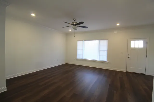an empty room with wooden floor chandelier fan and windows