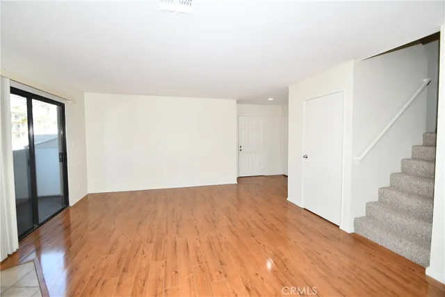 a view of a big room with wooden floor and entryway