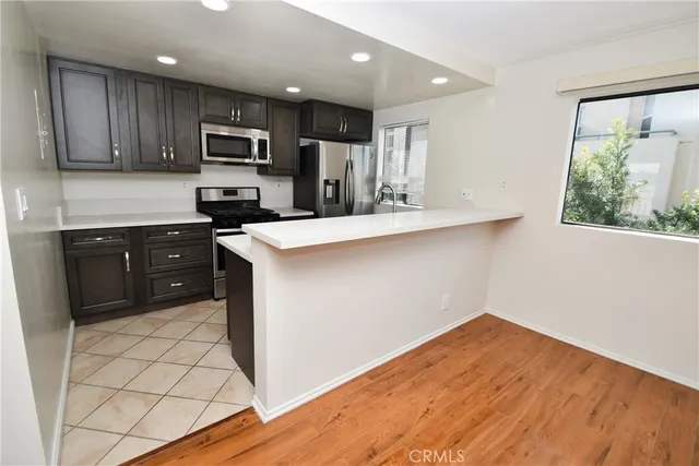 a kitchen with stainless steel appliances a sink a stove a refrigerator cabinets and a window